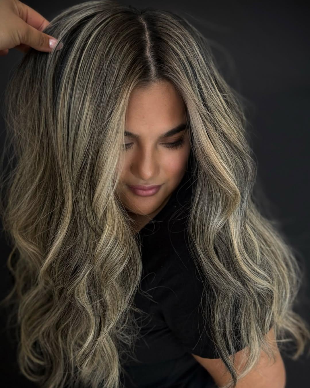 Very long ash blonde hair with hand-tied extensions, styled in soft waves