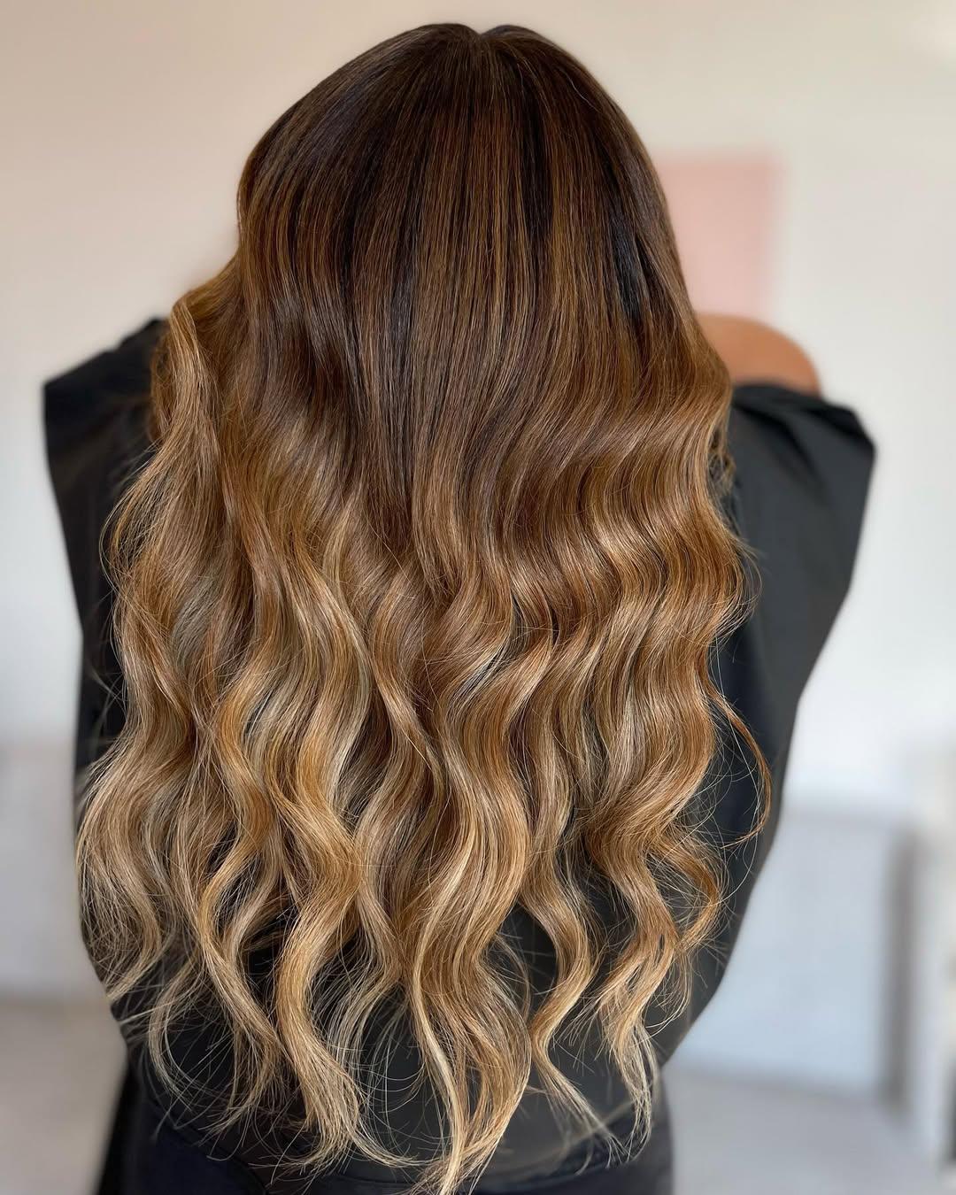 Long caramel waves with a deliberately deep, shadowed root